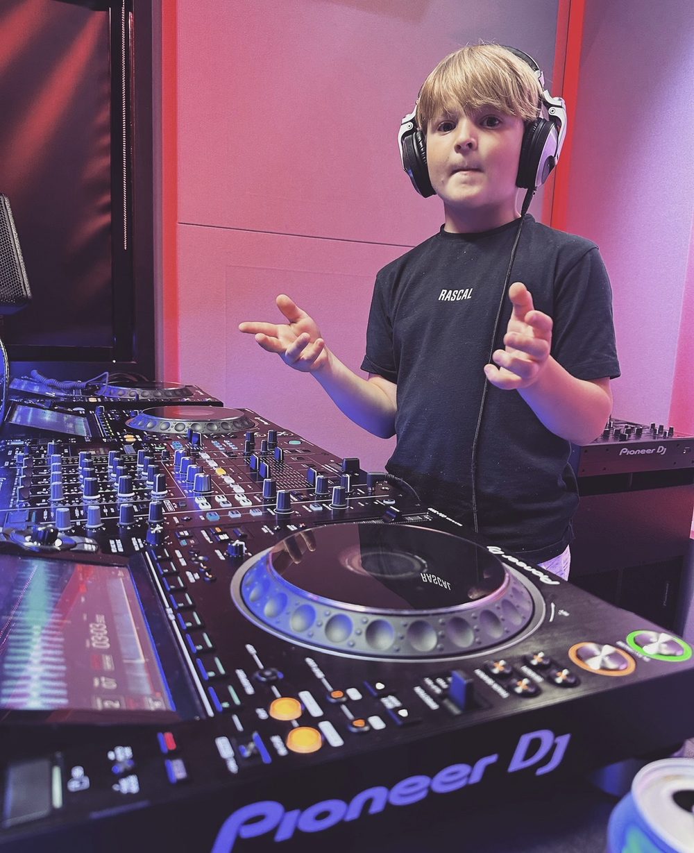 DJ Archie on Pioneer DJ decks in the studio, wearing headphones